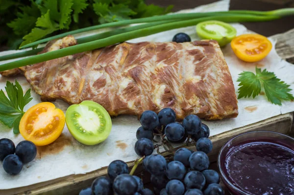 Costillas de cerdo ahumadas con salsa de uva, hierbas y verduras. Fondo de madera. Vista superior. Primer plano —  Fotos de Stock