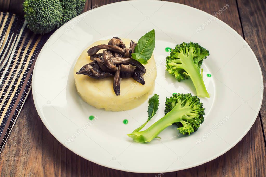 Mashed potatoes with mushrooms and boiled broccoli  sauce. Wooden background. Top view. Close-up