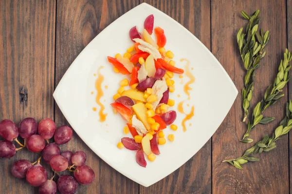 ブドウと白い皿に鶏のサラダ。木製の背景。トップ ビュー — ストック写真