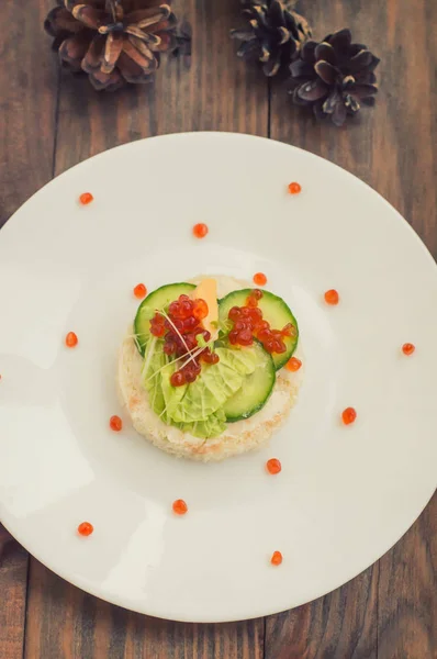 Gesunde Vorspeise: Sandwich mit Meereslachs und rotem Kaviar auf weißem Porzellanteller. Holzuntergrund. Ansicht von oben — Stockfoto