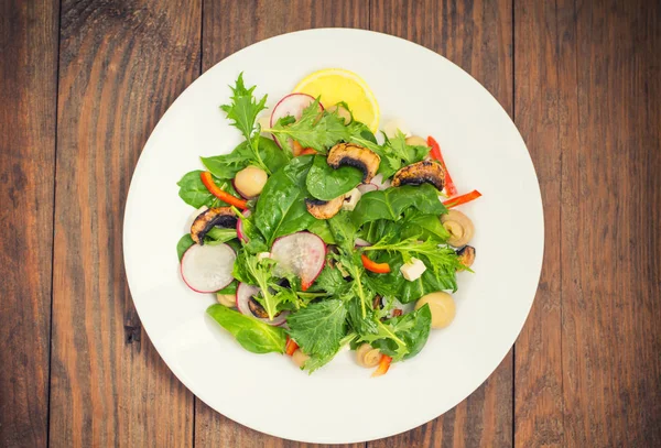 Verse lente salade met radijs, Mizuno, paddestoelen gegrild, Adygei kaas, spinazie, paprika, citroen, maïs. Houten achtergrond — Stockfoto