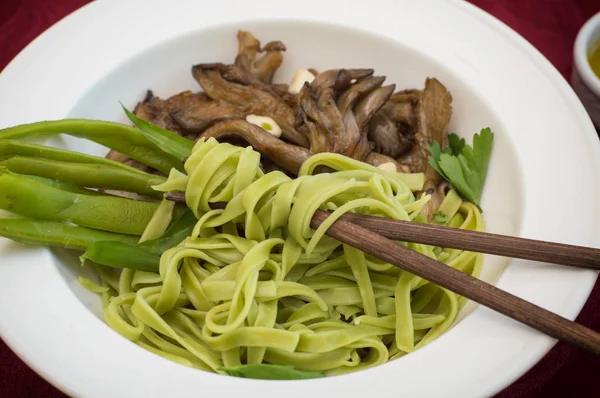 Piatto di pasta di spaghetti con spinaci e funghi ostrica. Cucina italiana, ricette italiane. Sfondo in legno. Vista dall'alto. Primo piano — Foto Stock