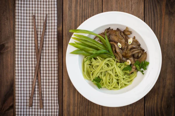 Piatto di pasta di spaghetti con spinaci e funghi ostrica. Cucina italiana, ricette italiane. Sfondo in legno. Vista dall'alto. Primo piano — Foto Stock