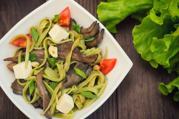 Assiette de pâte à spaghetti aux épinards et aux champignons aux huîtres. Cuisine italienne, recettes italiennes. Fond en bois. Vue de dessus. Gros plan — Photo