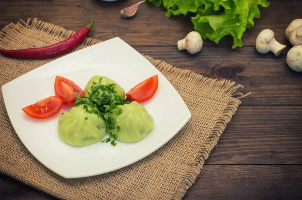 Georgische dumplings Khinkali van spinazie deeg met vlees en tomaat pikante saus satsebeli. Houten achtergrond. Bovenaanzicht. Close-up — Stockfoto