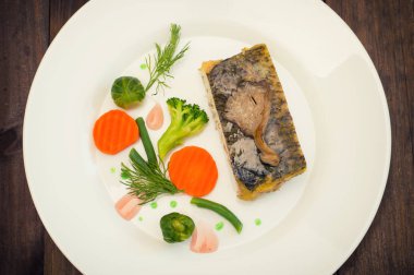 Lezzetli Fırında Balık plaka üzerinde tablo yakın çekim. Ahşap arka plan. Üstten Görünüm. Yakın çekim