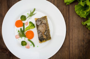 Lezzetli Fırında Balık plaka üzerinde tablo yakın çekim. Ahşap arka plan. Üstten Görünüm. Yakın çekim