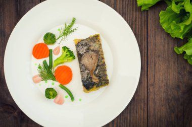 Lezzetli Fırında Balık plaka üzerinde tablo yakın çekim. Ahşap arka plan. Üstten Görünüm. Yakın çekim