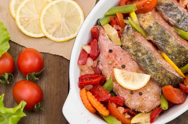 スズキと野菜。オーブンで調理用野菜マリネ魚。木製の背景。平面図です。クローズ アップ — ストック写真