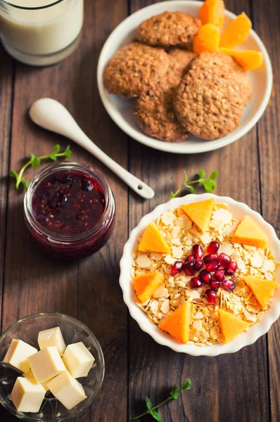 Ein leichtes Frühstück mit Müsli, Marmelade, Milch, Keksen und Obst. Holzuntergrund. Ansicht von oben. Nahaufnahme — Stockfoto