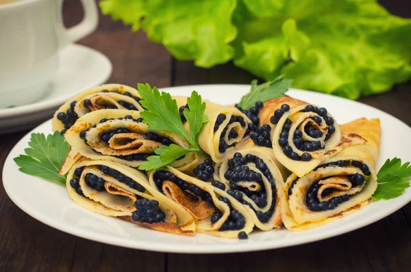 Rollos panqueques con caviar negro. Cocina rusa. Acostado. Maslenitsa. Fondo de madera. Primer plano —  Fotos de Stock