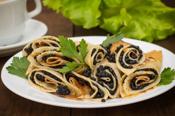 Rotoli frittelle con caviale nero. Cucina russa. Piatto. Maslenitsa. Sfondo in legno. Primo piano — Foto Stock