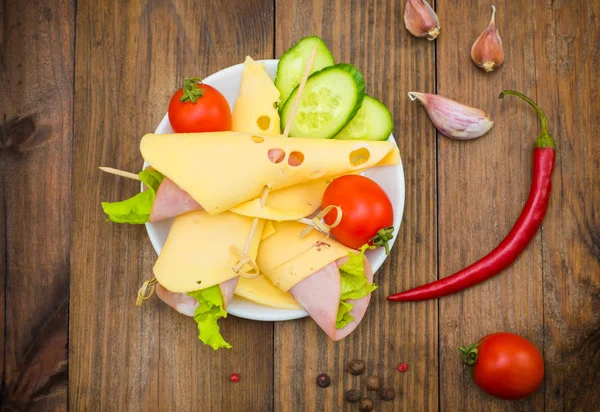 スライス チーズ、ソーセージ、野菜、トマトのカナッペ。木製の背景。平面図です。クローズ アップ — ストック写真