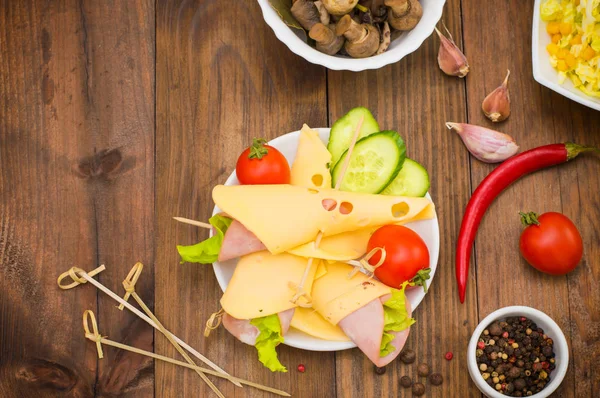 Trancher la canape avec le fromage, la saucisse, les légumes verts et la tomate. Fond en bois. Vue de dessus. Gros plan — Photo