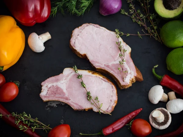 Geräucherte Schweinerippchen mit Gemüse auf schwarzem Steinhintergrund. Ansicht von oben. Nahaufnahme — Stockfoto