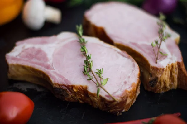 Gerookt varkensvlees ribben met groenten op een zwarte achtergrond van de stenen. Bovenaanzicht. Close-up — Stockfoto