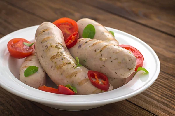 Saucisses grillées bouillies aux tomates cerises et aux piments verts. Fond en bois. Vue de dessus. Gros plan — Photo