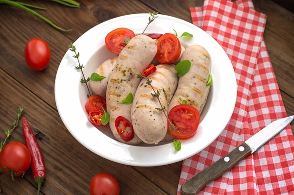 Embutidos a la parrilla hervidos con tomates cherry y chiles con verduras. Fondo de madera. Vista superior. Primer plano — Foto de Stock