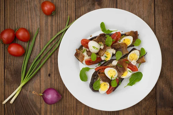 Bakad aubergine med bacon, vitlök och vaktelägg. Trä bakgrund. Ovanifrån. Närbild — Stockfoto