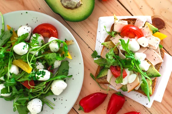 Salada com mussarela, rúcula e sanduíche com abacate, presunto. W — Fotografia de Stock