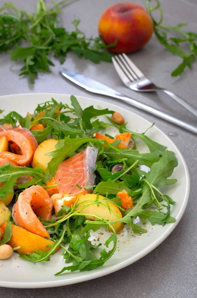 Salad with salmon, arugula, peach and peanuts. Rustic style. Gray stone background. Close-up. Top view — Stock Photo, Image