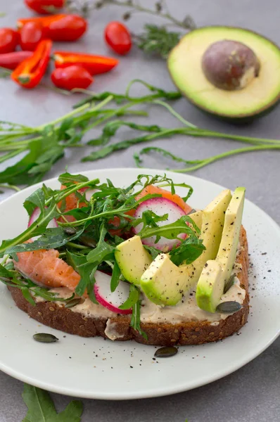 Sandwich maison avec avocat, saumon, roquette et humus. Style rustique. Fond en pierre grise. Gros plan. Vue du dessus — Photo