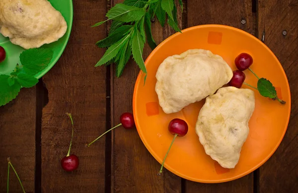 Hemlagade kroppkakor med körsbär. Trä bakgrund. Ovanifrån. Närbild — Stockfoto