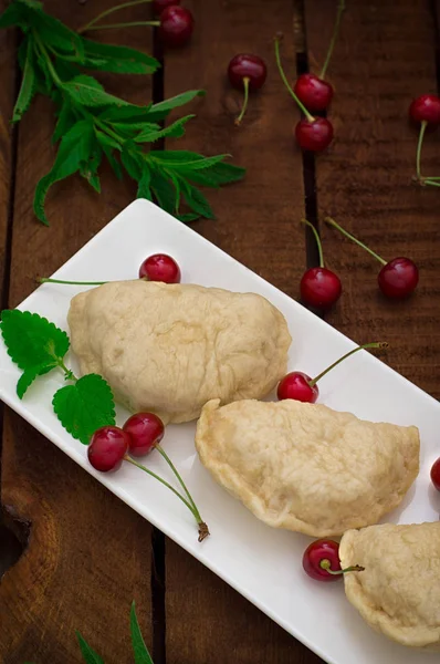 Hemlagade kroppkakor med körsbär. Trä rustik bakgrund. Närbild. Ovanifrån — Stockfoto