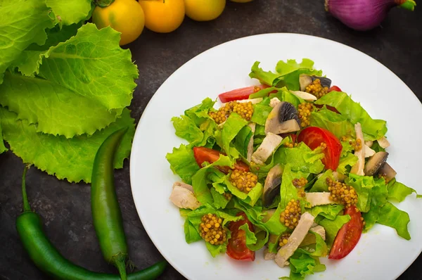 Ensalada fresca con pollo, champiñones, lechuga, tomate y mostaza. Fondo de piedra oscura. Vista superior. Primer plano — Foto de Stock