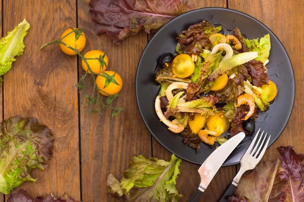 Frische Mischung Salat mit Garnelen, gelben Kirschtomaten und Balsamico-Sauce. auf Holzgrund. Nahaufnahme. Ansicht von oben — Stockfoto