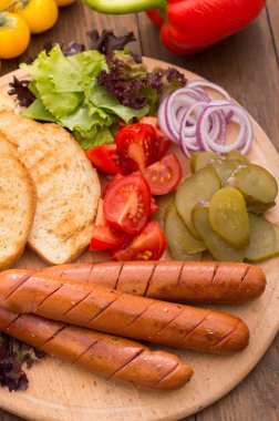 Gıda koymak sosis, sucuk, konserve salatalık, marul yaprakları, domates, soğan, kruton ahşap arka plan üzerinde. Yakın çekim. Üstten Görünüm