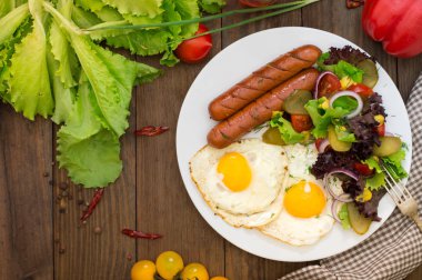 İngiliz kahvaltısı - ekmek, yumurta, sosis ve sebze salatası. Ahşap rustik arka plan. Yakın çekim. Üstten Görünüm