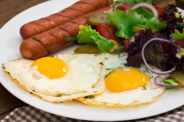 İngiliz kahvaltısı - ekmek, yumurta, sosis ve sebze salatası. Ahşap rustik arka plan. Yakın çekim. Üstten Görünüm