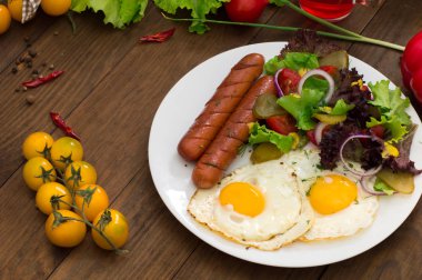 İngiliz kahvaltısı - ekmek, yumurta, sosis ve sebze salatası. Ahşap rustik arka plan. Yakın çekim. Üstten Görünüm