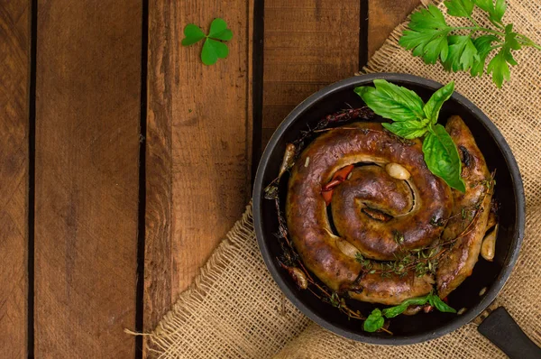 Ev yapımı domuz sosisi kekik ile tavada. Rustik ahşap arka plan. Yakın çekim. Üstten Görünüm