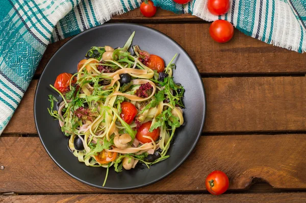 Bucatini italien aux crevettes, roquette et tomates cerises. Fond en bois. Gros plan. Vue du dessus — Photo