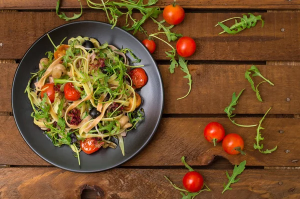 Bucatini italien aux crevettes, roquette et tomates cerises. Fond en bois. Gros plan. Vue du dessus — Photo