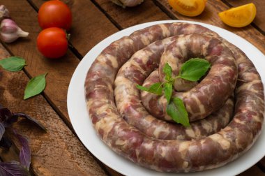 Ahşap arka plan üzerinde beyaz bir tabak içinde ham taze sosis. Üstten Görünüm. Yakın çekim