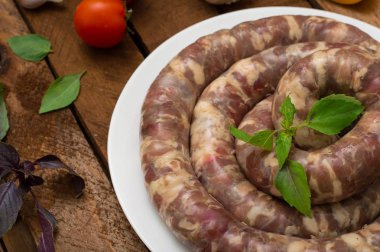 Ahşap arka plan üzerinde beyaz bir tabak içinde ham taze sosis. Üstten Görünüm. Yakın çekim