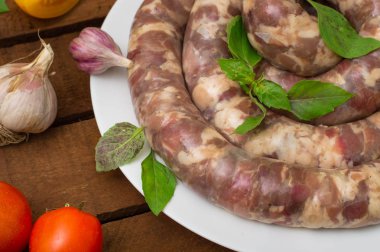 Ahşap arka plan üzerinde beyaz bir tabak içinde ham taze sosis. Üstten Görünüm. Yakın çekim