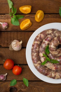 Ahşap arka plan üzerinde beyaz bir tabak içinde ham taze sosis. Üstten Görünüm. Yakın çekim