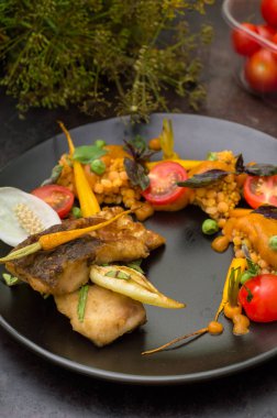 Mercimek, yeşil bezelye, kayısı sos, bebek havuç ve domates ile kızarmış balık yemek. Eski siyah arka plan. Yakın çekim. Üstten Görünüm