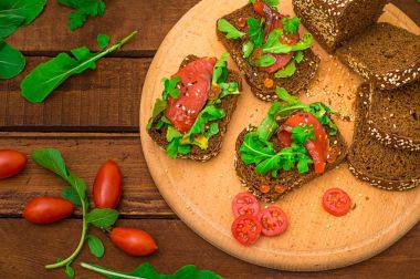 Bruschetta somon balığı, kırmızı balık, kırmızı havyar, roka ve domates bir gemide. Ahşap rustik arka plan. Seçici odak. Üstten Görünüm