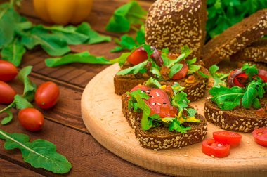 Bruschetta somon balığı, kırmızı balık, kırmızı havyar, roka ve domates bir gemide. Ahşap rustik arka plan. Seçici odak. Üstten Görünüm