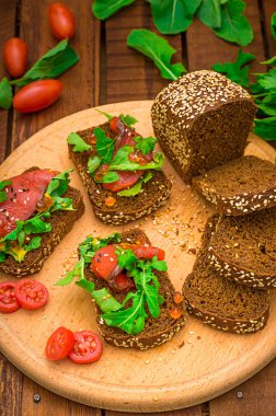 Bruschetta somon balığı, kırmızı balık, kırmızı havyar, roka ve domates bir gemide. Ahşap rustik arka plan. Seçici odak. Üstten Görünüm