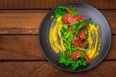 Salata somon, roka, kırmızı havyar ve Hollandalı sos Hollandez. Ahşap rustik arka plan. Üstten Görünüm. Seçici odak