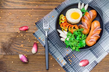 Kızarmış yumurta sosis, rucola, biber ve turp. Ahşap rustik arka plan. Seçici odak. Üstten Görünüm