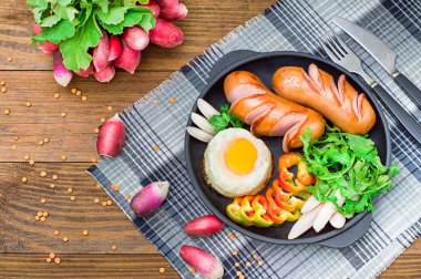 Kızarmış yumurta sosis, rucola, biber ve turp. Ahşap rustik arka plan. Seçici odak. Üstten Görünüm