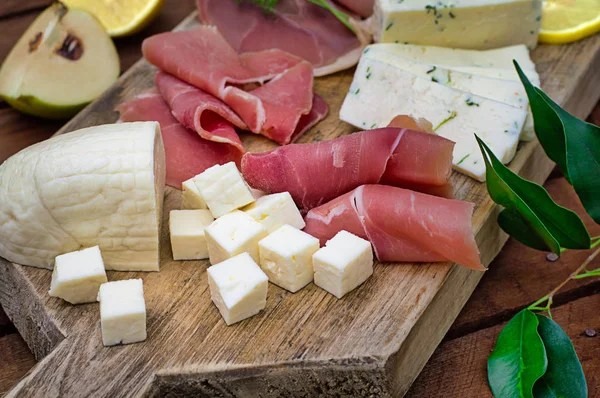 Jamon avec différents types de fromage sur une planche en bois. Fond rustique en bois. Vue du dessus — Photo