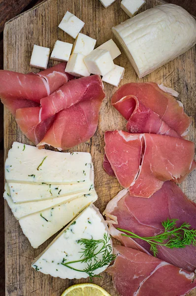 Jamon avec différents types de fromage sur une planche en bois. Fond rustique en bois. Vue du dessus — Photo